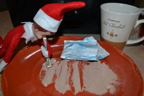 Elf On The Shelf doing lines of 'drugs' with cocoa powder